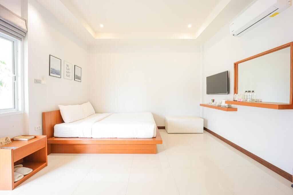 Quarto moderno com cama de madeira, mesa de cabeceira, TV e um espelho grande.