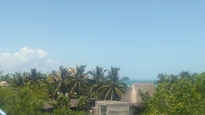 A tropical landscape with palm trees and a thatched-roof structure. - Casa Vainilla (Isla Holbox)