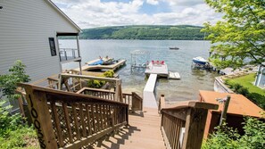 Une terrasse donnant sur un quai où sont amarrés des bateaux, une maison et offrant une vue sur le lac.