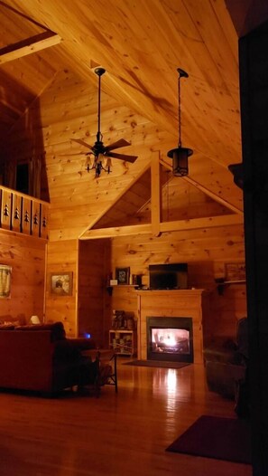 Ein gemütliches Blockhaus-Interieur mit Kamin, Holzwänden und Deckenventilator.