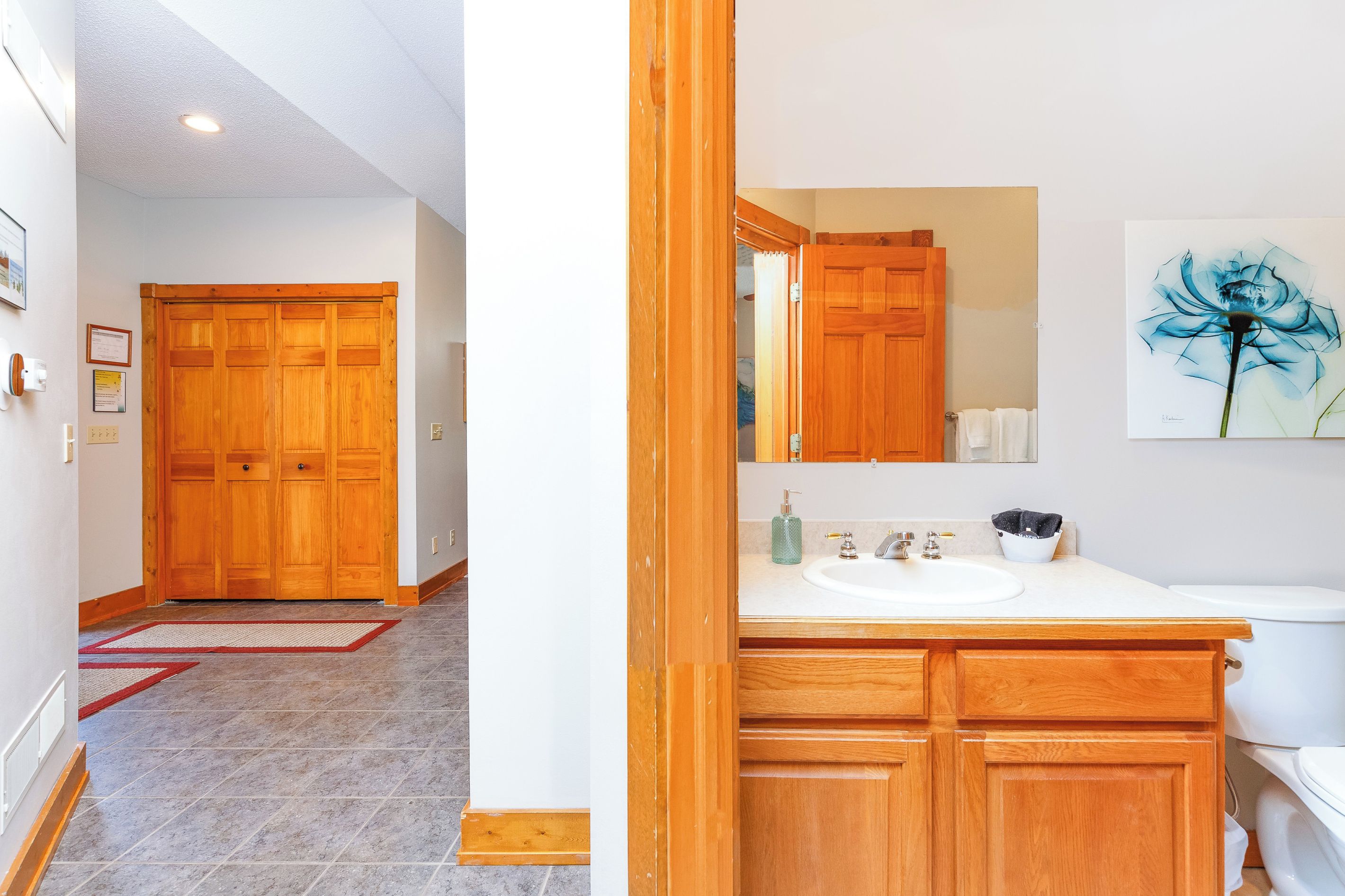 Un bagno con mobili in legno, un lavandino e uno specchio grande.