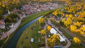 An aerial view of a town with a river, buildings, and a large open field with tents.