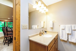 Une salle de bain avec un grand miroir, un lavabo et un porte-serviettes.