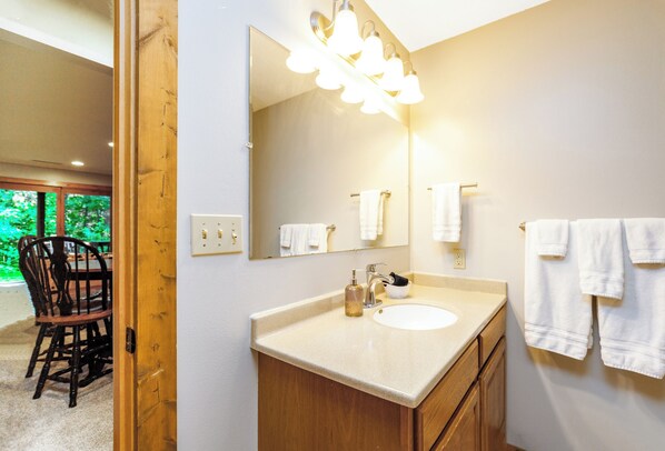 Un baño con un espejo grande, un lavabo y un perchero para toallas.