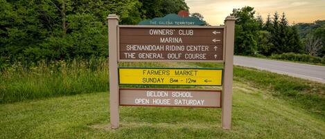 Uma placa de sinalização com vários destinos, incluindo Owners' Club, Marina, Shenandoah Riding Center, The General Golf Course, Mercado dos Agricultores e Belden School.