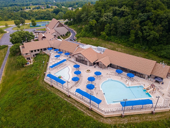 A resort with multiple swimming pools, outdoor seating areas, and a large building with a distinctive roof.