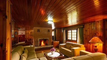 A cozy living room with a fireplace, wooden walls, and a comfortable seating area.