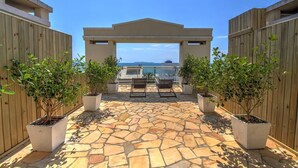 A stone-tiled patio with two chairs and a pergola, surrounded by wooden fences and potted plants. - Pousada Pedra Salgada (Bombinhas)