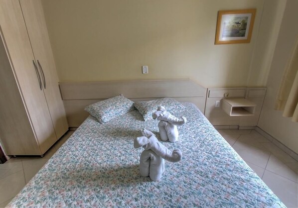 Un dormitorio con cama, dos almohadas, una mesita de noche y un armario.