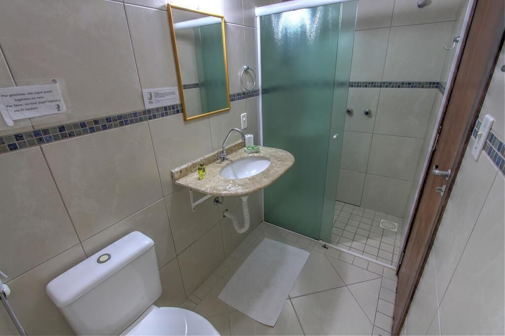 A bathroom with a sink, mirror, toilet, and shower.