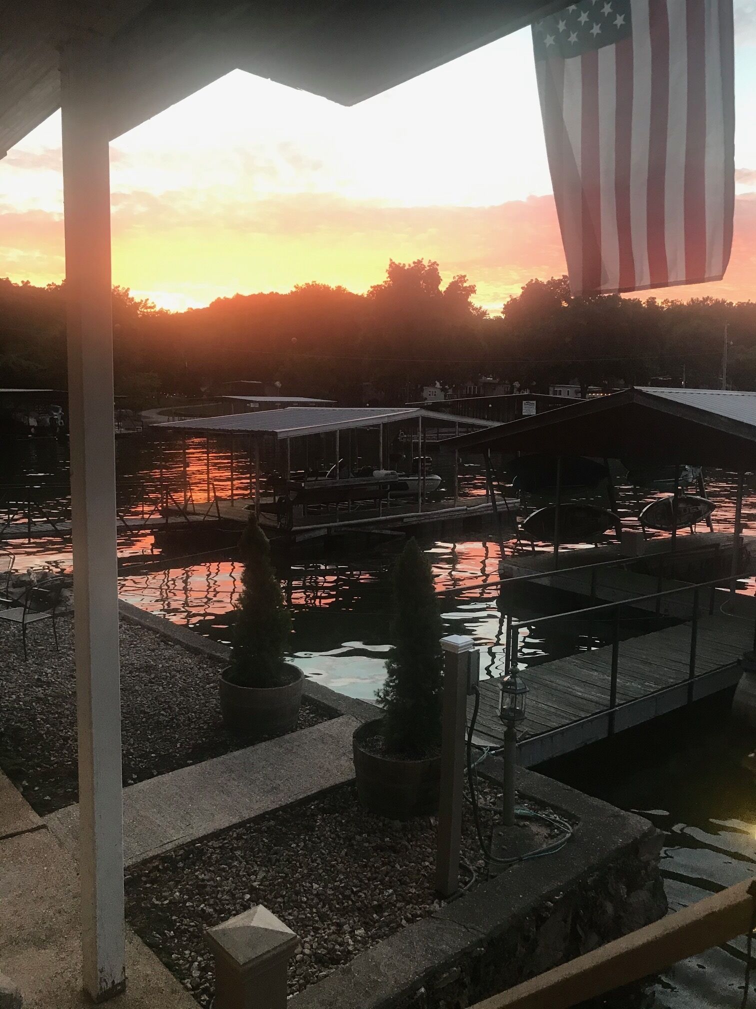 A waterfront area with docked boats, a covered seating area, and an American flag.