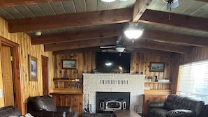 A cozy living room with a fireplace, leather sofas, and wooden paneling. - Martin's Hideout in Greer AZ (Greer)