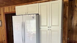 A white refrigerator with a freezer drawer, placed in a wooden-paneled kitchen with cabinets. - Martin's Hideout in Greer AZ (Greer)