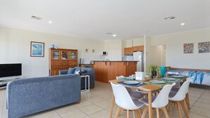 A modern apartment with a living room, dining area, and kitchenette.