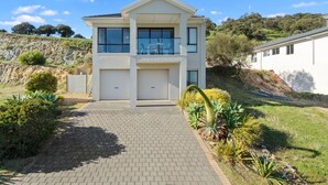 A modern two-story house with a paved driveway, large windows, and a garage.