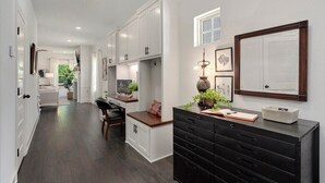 Una cocina moderna con armarios blancos, encimera negra y una mesa de comedor de madera.