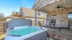 Un patio trasero con jacuzzi, mobiliario de exterior y una parrilla.