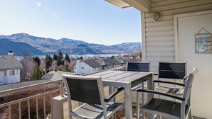 A balcony with a table and chairs, overlooking a mountainous landscape and a body of water. - Park Pointe C201 - Community Pool/Hot tub (Chelan)