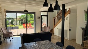 Una sala de estar moderna con comedor, una escalera y vista al jardín.