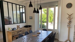 Un comedor con una mesa cubierta con un mantel de lunares, rodeada de sillas. Un mueble de madera con un espejo y objetos decorativos está contra la pared.