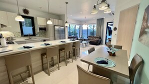 Une cuisine moderne dotée d’un îlot central, de tabourets de bar et d’une table à manger avec des chaises.