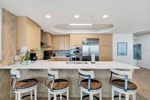 A modern kitchen with a central island, stainless steel appliances, and a tiled backsplash. - Modern Style Meets Coastal Chic in this Beautiful Spacious Unit! Complimentary Boat Slip! (Orange Beach)