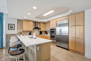 A modern kitchen with a central island, stainless steel appliances, and wooden cabinetry.