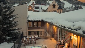 A snow-covered outdoor area with a hot tub, wooden chairs, and a view of a mountain. - Dog Friendly Vail Lionshead Studio, LH Studio (Vail)