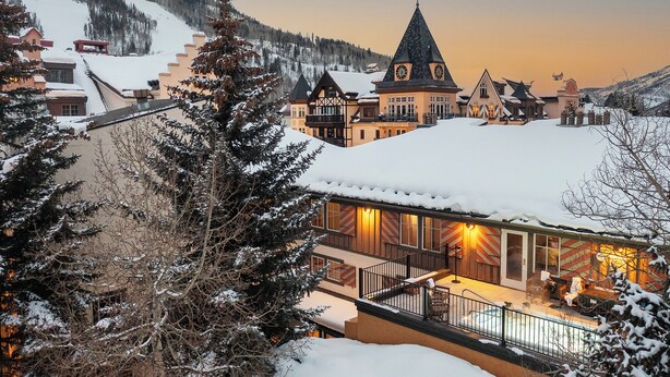 A snow-covered town with traditional architecture, including a prominent building with a pointed roof and a balcony with outdoor seating. - Dog Friendly Vail Lionshead Studio, LH Studio (Vail)
