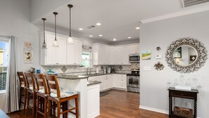 Una cocina moderna con armarios blancos, una isla central e iluminación colgante.