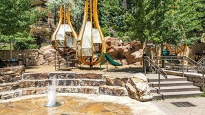 A stone fountain, outdoor seating with yellow canopies, and a playground with a slide. - Remodeled, 100m Walk Lionshead Gondola, LH Premium (Vail)