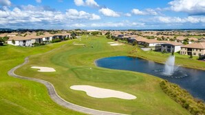 Un parcours de golf avec des bunkers, un étang et une fontaine.