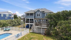 A two-story house with a pool, deck, and a staircase leading to a second level. - 1517 - Drift Inn - Steps to Beach | Pool, Hot Tub & Pet Friendly (Corolla)