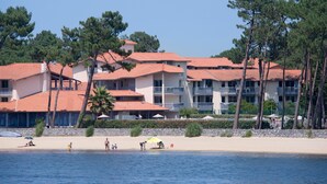 Een kusthotel met meerdere balkons en een strand op de achtergrond.