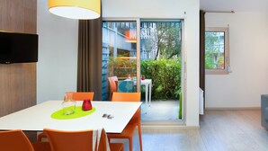 Een moderne eethoek met een witte tafel, oranje stoelen en een glazen vaas.