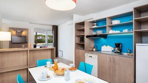 Een moderne keuken met houten kastjes, een eettafel met stoelen en een ontbijtsetting.