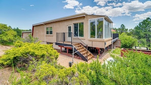 Ein modernes Haus mit großem Glasfenster, einer Treppe und einem Garten.