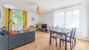 A modern living room with a sofa, dining table, and TV. - Appartement Mansana - Welkeys (Caluire-et-Cuire)