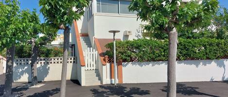 A modern building with a white facade, a staircase, and a gated entrance.