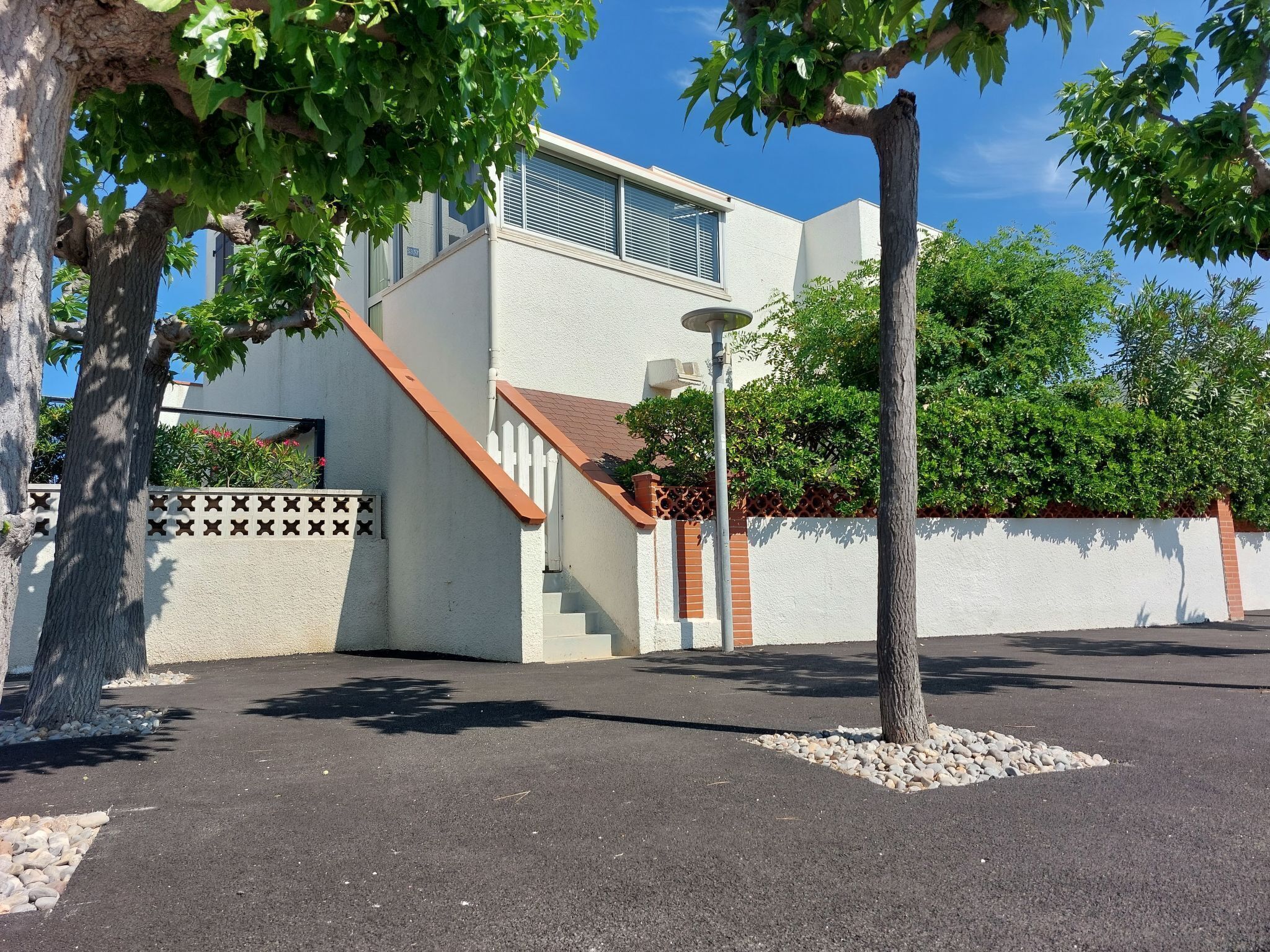 A modern building with a white exterior, a red roof, and a staircase leading to a second floor.