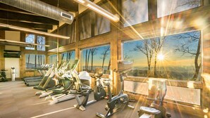 Una palestra con diverse attrezzature per l'allenamento, ampie finestre e viste panoramiche, e un design architettonico moderno.