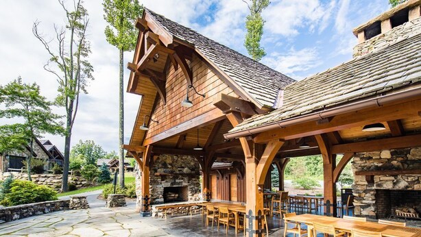Un rifugio rustico con camino in pietra, tavoli di legno e un patio in pietra.