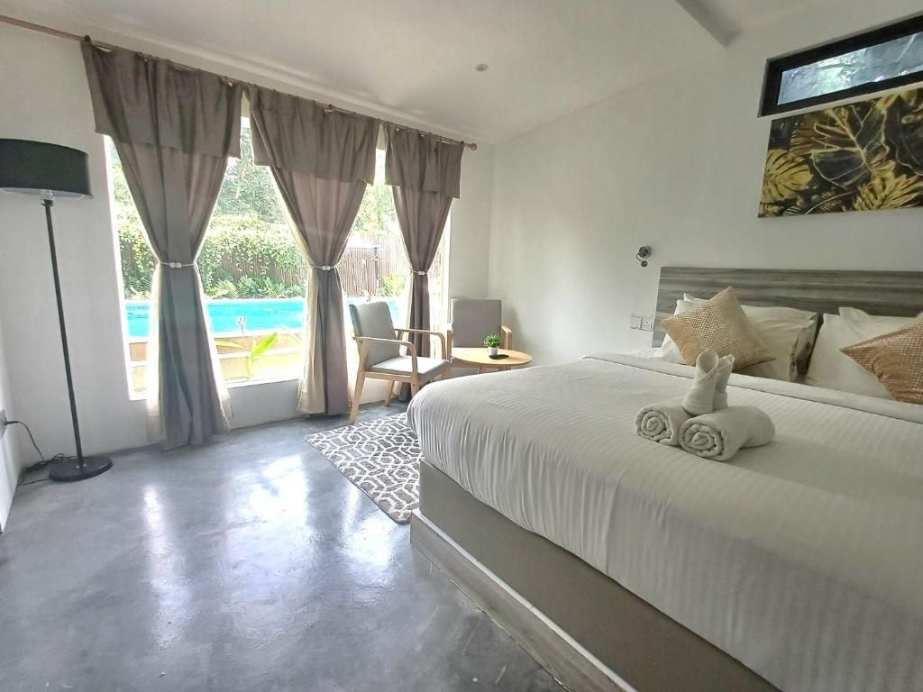 A hotel room with a large bed, a desk, a chair, and a view of the outdoors.