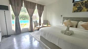 A hotel room with a large bed, a desk, a chair, and a view of the outdoors.
