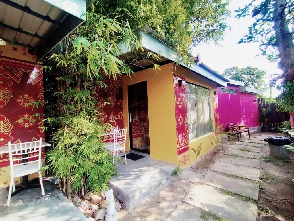A building with a covered entrance, a small outdoor seating area with a table and chairs, and a staircase leading to a door.