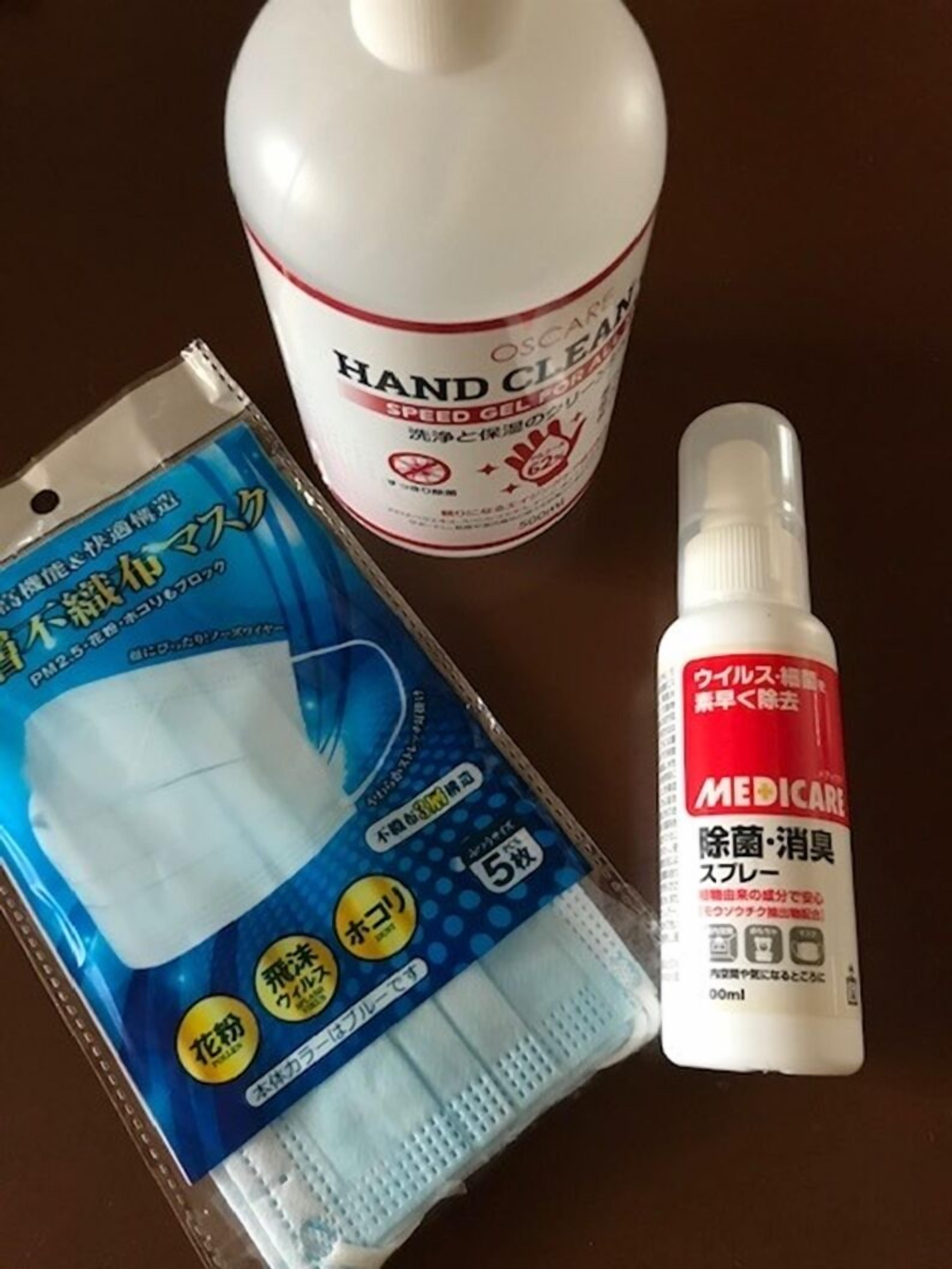 A package of disposable masks, a bottle of hand sanitizer, and a spray bottle.