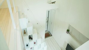 A modern interior with a staircase, white walls, and a small plant on the wall.