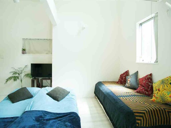 A bedroom with two beds, a TV, a small plant, and a window. - Just 9 minutes from the famous Shibuya Crossing and a stone's throw from Ebisu, Nakameguro, and Daikanyama! A stylish new room with a loft is now open. (Shibuyaku Higashi)