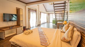 Habitación de hotel con cama, televisión, escritorio, silla y vistas a un balcón.