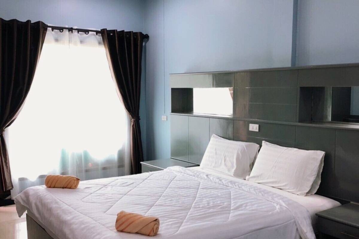 Ein modernes Hotelzimmer mit einem großen Bett, einem dunklen Kopfteil und einem Nachttisch mit Lampe.